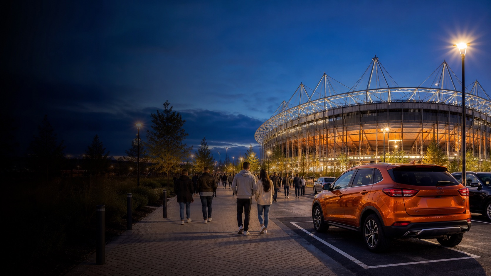 People walking from reserved parking toward an illuminated stadium