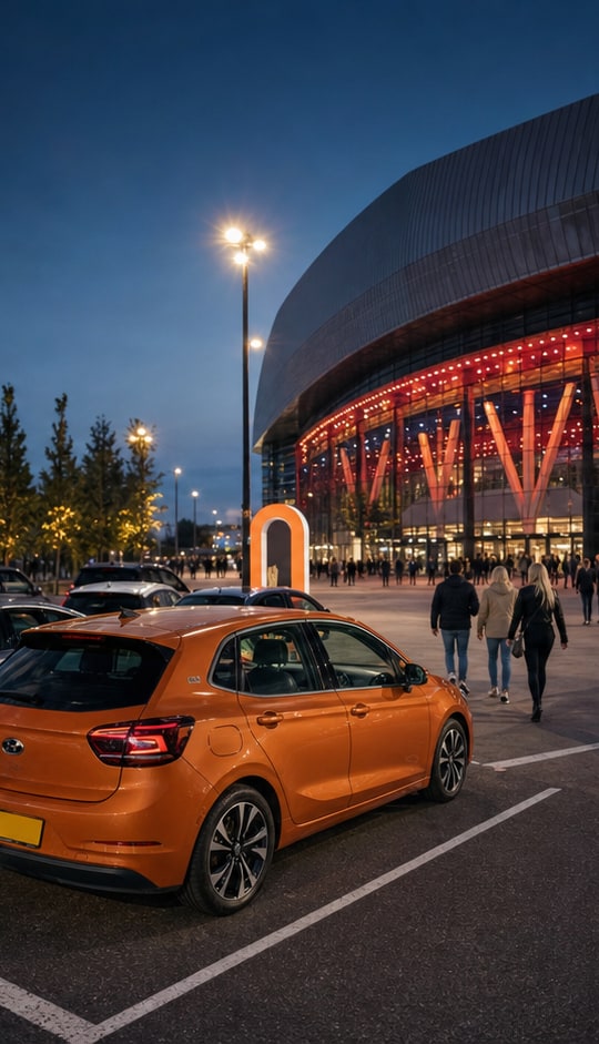 Orange car parked beside an illuminated arena